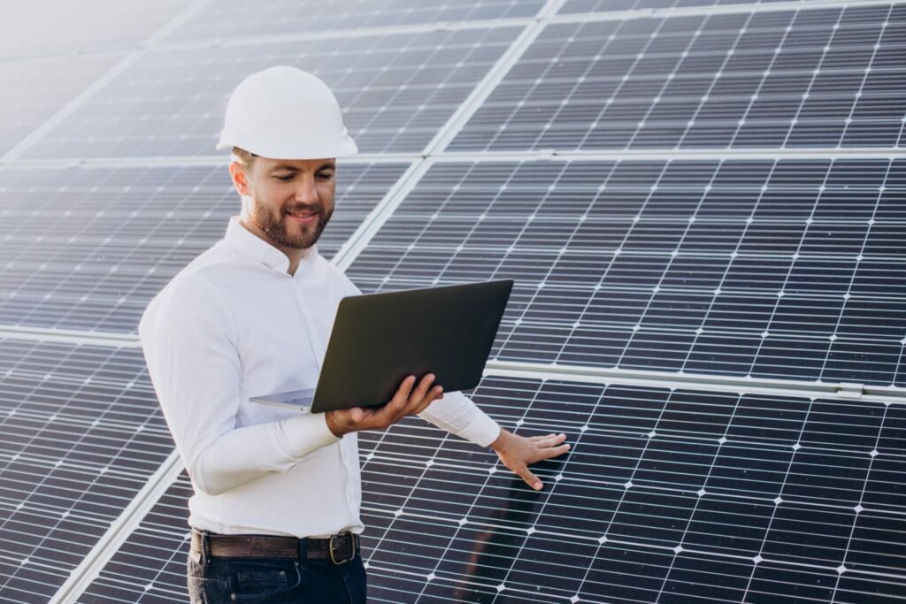 young architect standing by solar panels making diagnostics on computer 1 1